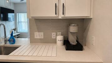 A kitchen with white cabinets, a coffee maker, a sugar container, and a Dawn dish soap bottle.