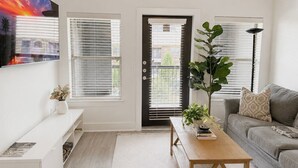 Una sala de estar moderna con un sofá, una mesa de centro y un televisor montado en la pared.