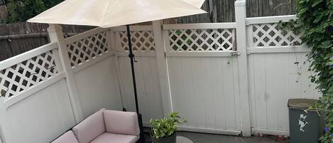 Eine Terrasse mit bequemen Sitzgelegenheiten, einem Blumentopf und einem Mülleimer.