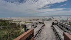 A wooden boardwalk leading to a beach with umbrellas and beach chairs. - 2-bedroom Condo in St. Augustine- Private Beach Beach Access + Pool! (St. Augustine)