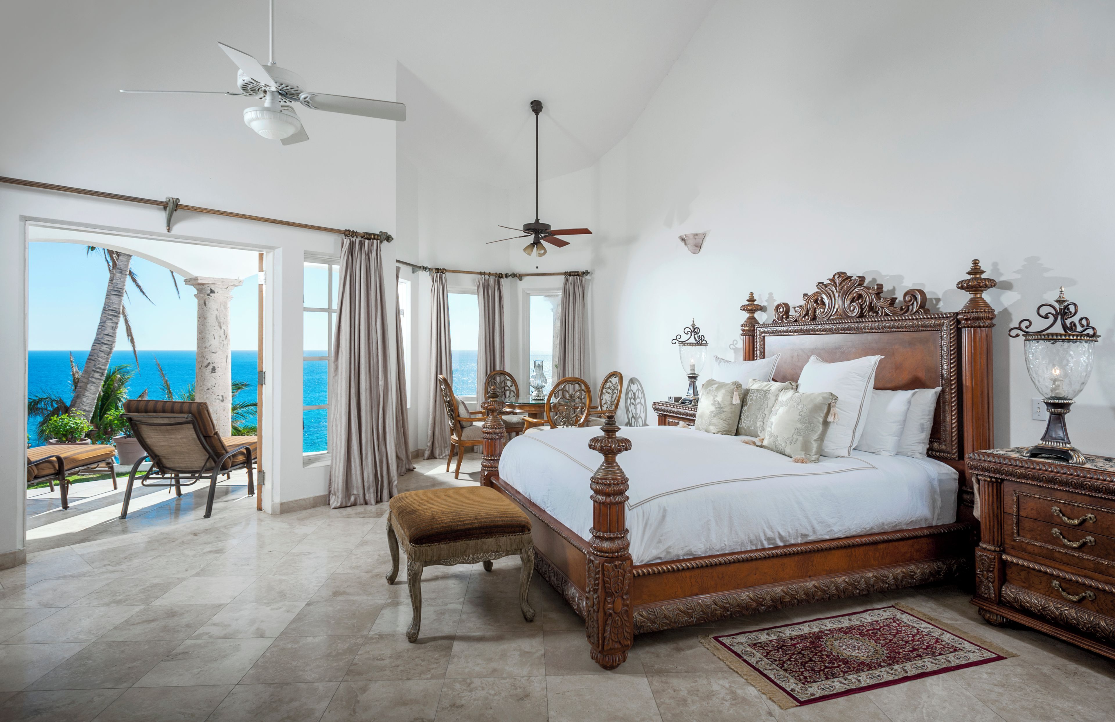 A spacious bedroom with a large bed, a ceiling fan, and a view of the ocean.