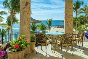 A patio with a table and chairs, a potted plant with red flowers, and a view of the ocean. - Villa Paraiso Ocean front 8-bedroom Villa in Palmilla Sur Private beach (Palmilla)