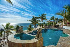 A pool with a stone sculpture, palm trees, and a view of the ocean. - Villa Paraiso Ocean front 8-bedroom Villa in Palmilla Sur Private beach (Palmilla)