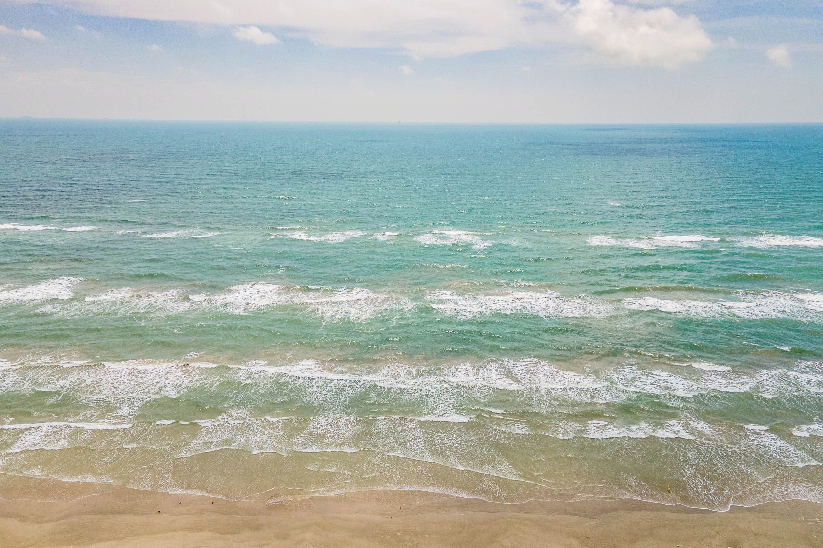 A beach with waves approaching the shore.