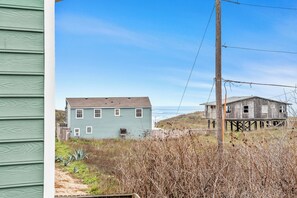 A coastal house with a wooden deck, a utility pole, and a clear sky. - Tan Lines and Fine Wines (Port Aransas)