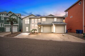 A residential house with a garage, a driveway, and a small garden. - Tan Lines and Fine Wines (Port Aransas)