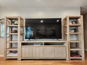 Een moderne entertainmentkast met een flatscreen televisie, houten planken en een console tafel.