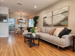 A living room with a sofa, coffee table, and artwork on the walls. - Comfy Courtyard 1 Bedroom at Jackson Market (Culver City)