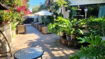 Un espace patio aménagé avec des sièges d’extérieur, une fontaine et des plantes en pot.