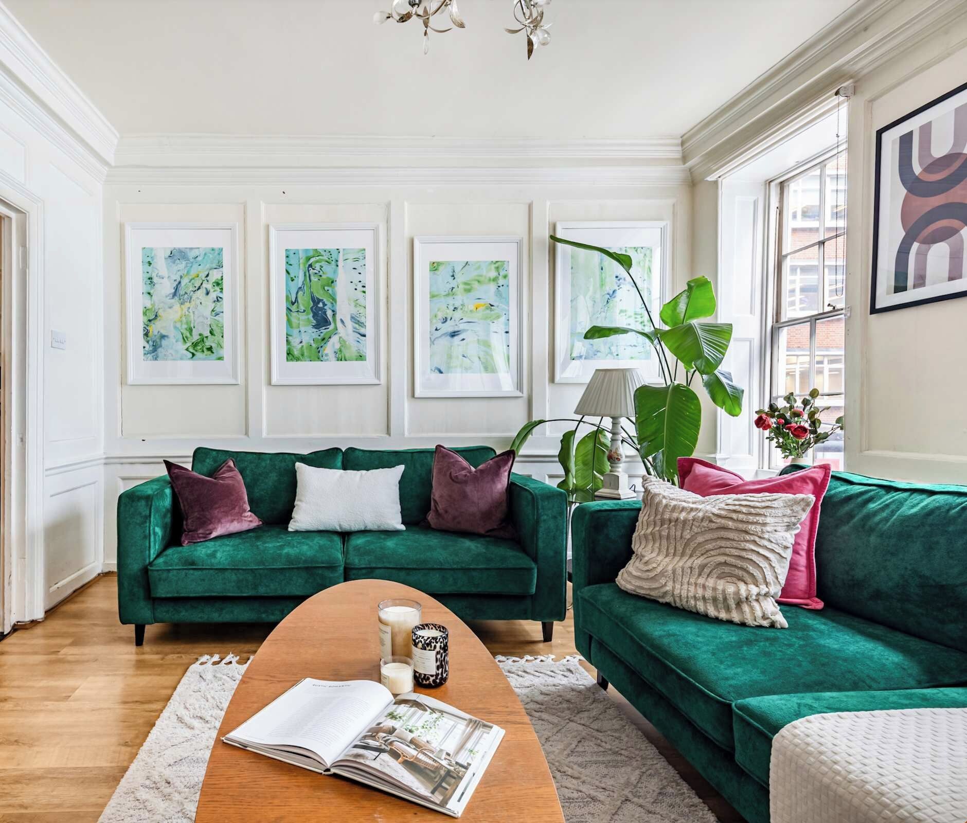 Ein Wohnzimmer mit zwei grünen Sofas, einem Couchtisch und einem großen Fenster.