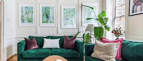 A living room with two green sofas, a coffee table, and a large window.