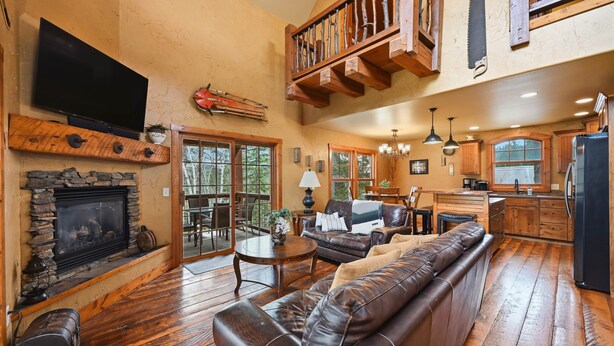 A spacious living room with a fireplace, leather sofa, and a television. - Mineral Mountain Lodge in Gilded Mountain (Lead)