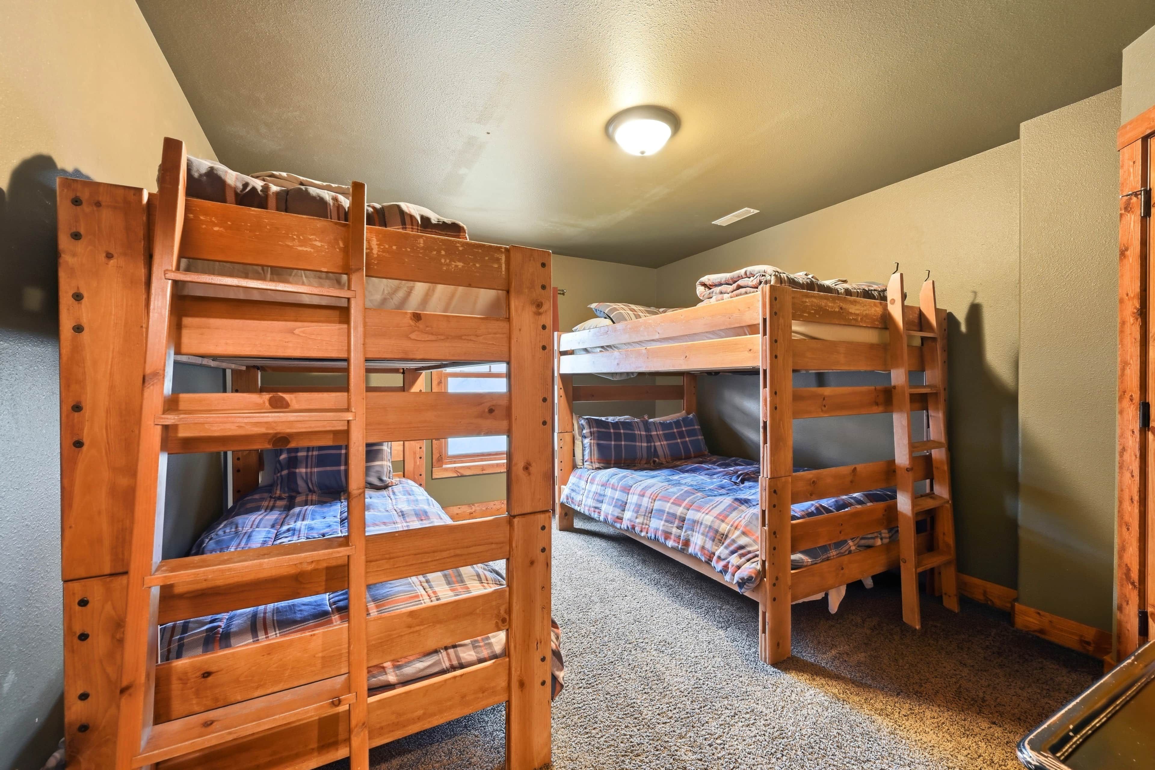 A room with two bunk beds, carpeted floor, and a ceiling light.