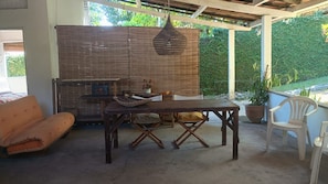 An outdoor patio with a table, two folding chairs, a sofa, and a hanging light fixture.