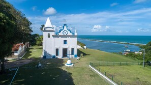A white church with a blue roof and a cross on top, located near a body of water.