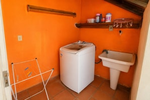 A compact laundry room with a washing machine, a sink, and a drying rack.