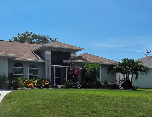 A residential house with a front porch, a garage, and a well-maintained lawn.