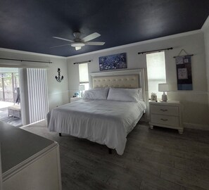 A bedroom with a bed, nightstands, a ceiling fan, and a window with blinds. - Beautiful home with heated saltwater pool in sought after Cape Coral, Florida. (Cape Coral)