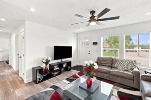 A modern living room with a flat-screen TV, a ceiling fan, a leather sofa, and a glass coffee table. - NEW Modern Contemporary West Side Retreat (Colorado Springs)