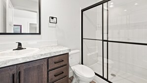 A modern bathroom with a large mirror, a sink, a toilet, and a glass shower enclosure. - NEW Modern Contemporary West Side Retreat (Colorado Springs)