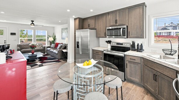 A modern kitchen with stainless steel appliances, a dining area with a glass table, and a view of a residential area. - NEW Modern Contemporary West Side Retreat (Colorado Springs)