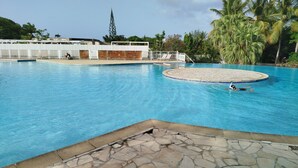 Una piscina con borde de piedra, un jacuzzi circular y sillas de descanso.