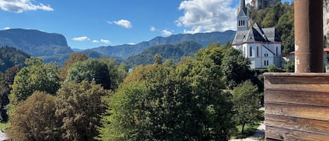 A view of a building with a prominent tower, surrounded by lush greenery and mountains in the background.