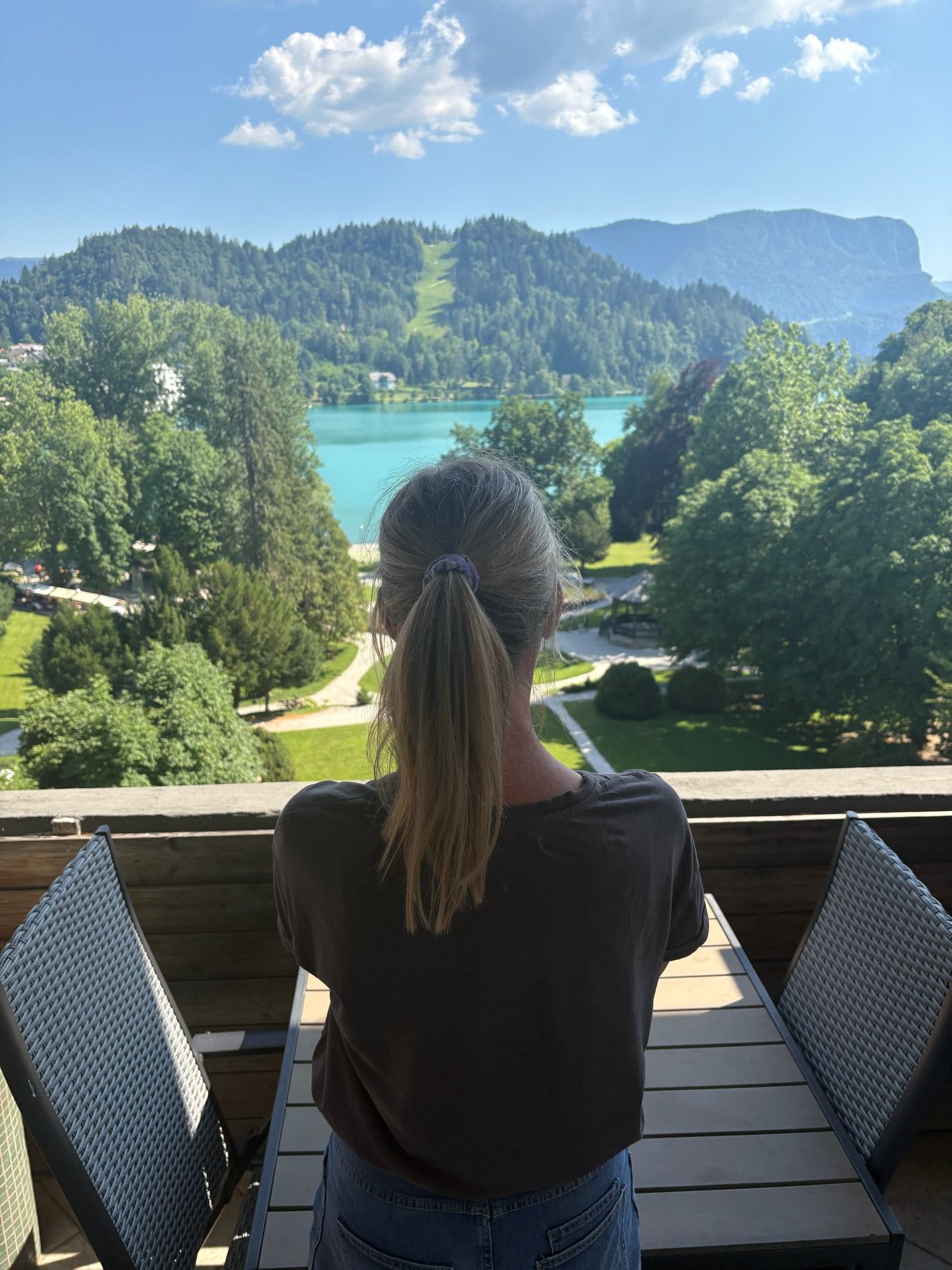 Una persona sentada a una mesa con vistas a un lago y montañas.
