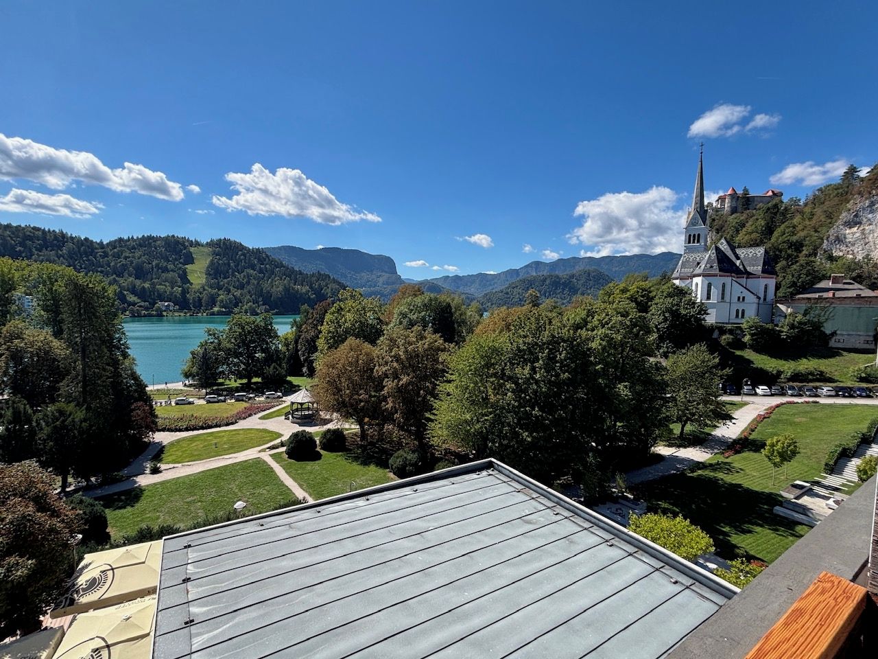 A view of a lake, a church, and a castle on a hill.