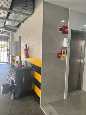 A fire extinguisher, an emergency exit sign, and a social elevator in a public building. - Spectacular apartment, well located, close to the city's shopping malls. (Salvador)