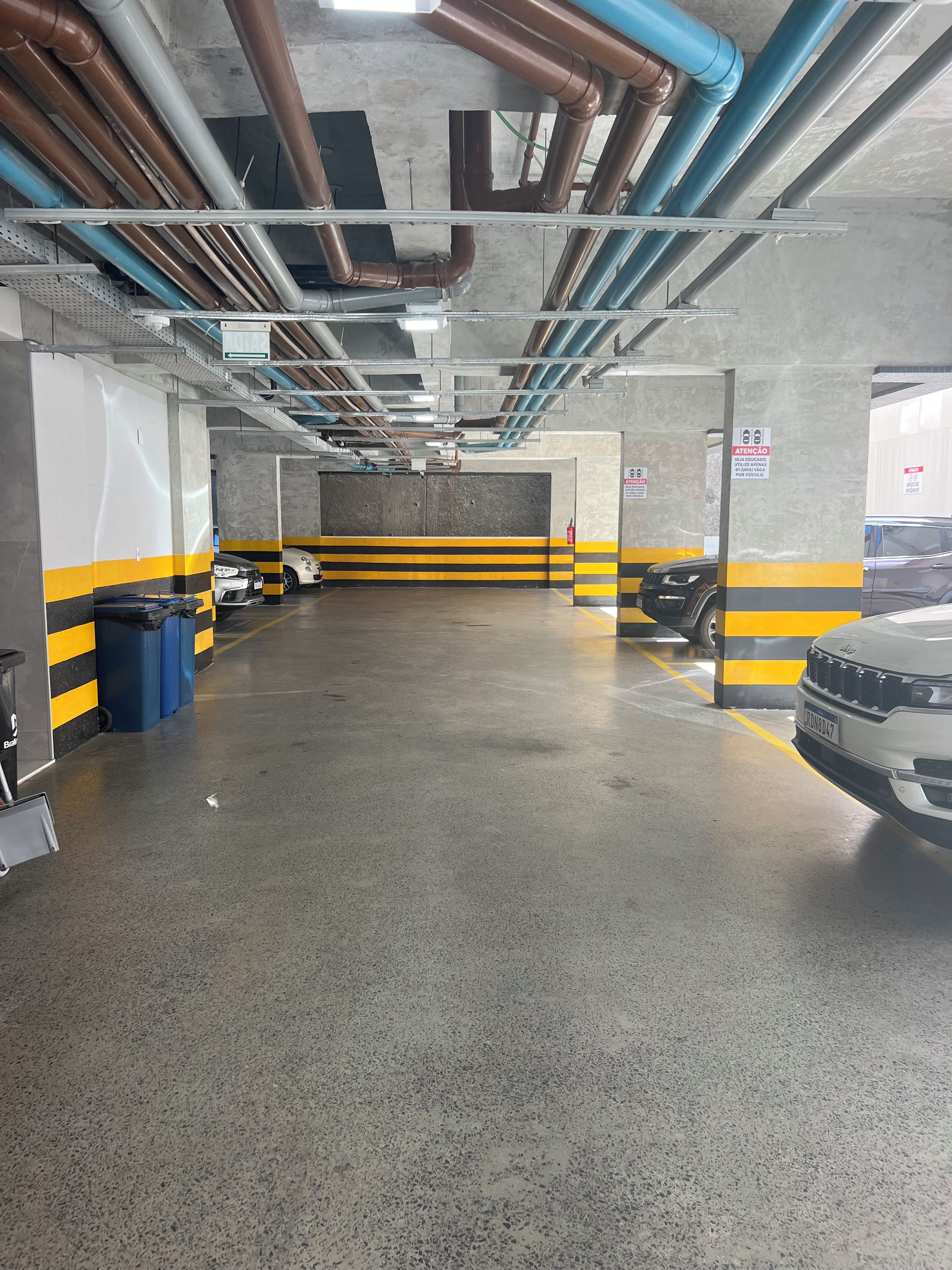 A parking garage with multiple levels, concrete walls, and a yellow and black striped safety line.