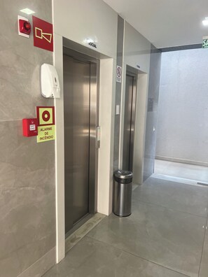 An elevator area with a fire alarm, a trash bin, and a no-smoking sign. - Spectacular apartment, well located, close to the city's shopping malls. (Salvador)