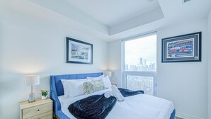 Une chambre à coucher moderne avec un grand lit, une table de chevet avec une lampe et des tableaux encadrés accrochés aux murs.