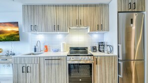 Une cuisine moderne avec des meubles en bois, des appareils électroménagers en acier inoxydable et un dosseret carrelé.