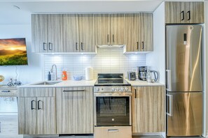 Une cuisine moderne avec des meubles en bois, des appareils électroménagers en acier inoxydable et un dosseret carrelé.