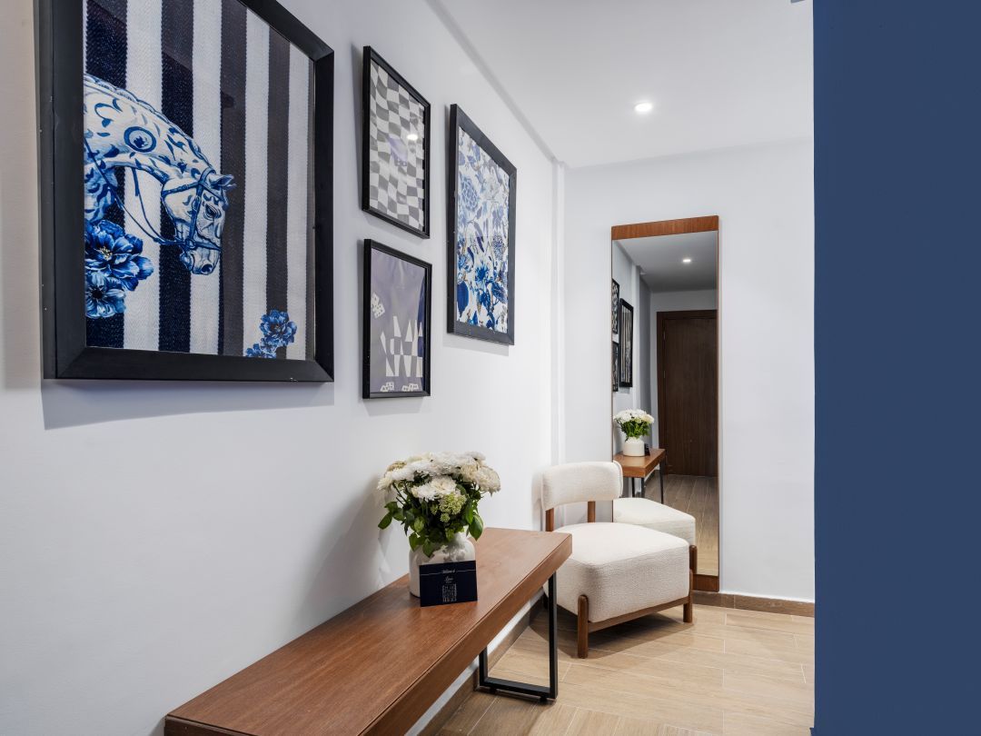 Ein modernes Interieur mit einer hölzernen Bank, einem weißen Stuhl und Kunstwerken an der Wand.