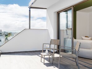 Un balcón moderno con vistas a un paisaje urbano, un sofá y dos sillones.