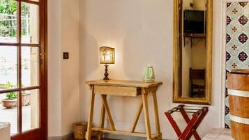A room with a wooden table, a lamp, a mirror, and a television.