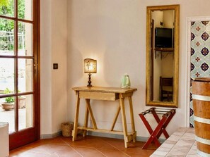 A room with a wooden table, a lamp, a mirror, and a television. - Hotel Sor Paolo (San Casciano in Val di Pesa)