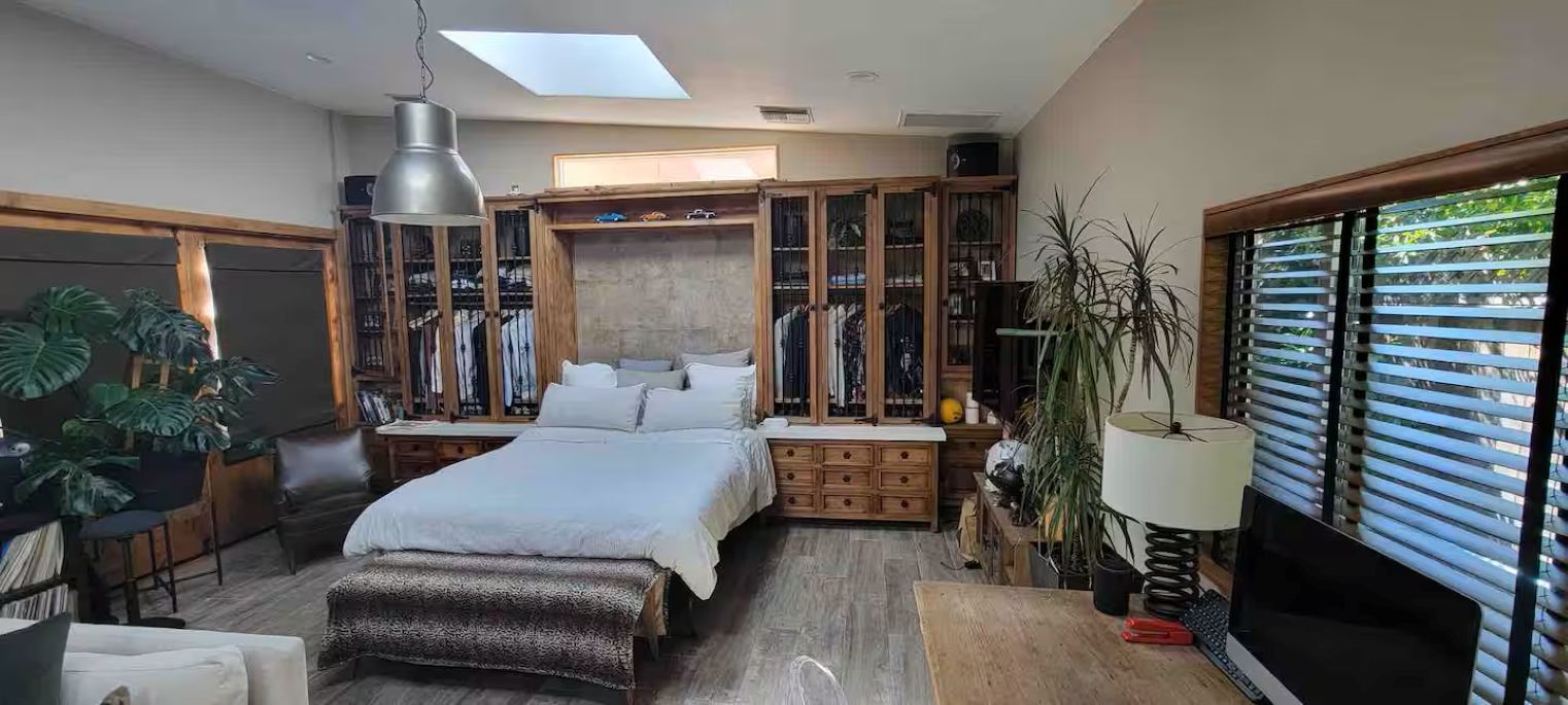 Quarto com cama, escrivaninha, cadeira, guarda-roupa e janela com persianas.