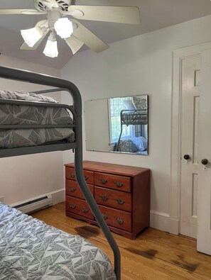 A bedroom with a bunk bed, a dresser, a mirror, and a ceiling fan. - Cozy Vermont retreat near Jay peak (Troy)