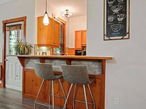 Eine Küche mit Holzausstattung, eine Bar mit zwei Hockern und eine Kreidetafel als Speisekarte an der Wand.