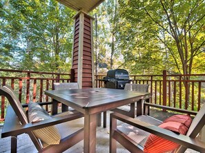 Eine Terrasse im Freien mit Grill, Holzmöbeln und Blick auf Bäume.