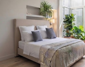 Un lit avec une tête de lit, des oreillers et une couverture. Il y a une étagère au-dessus du lit et une fenêtre sur la droite.