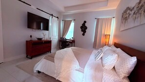 Un dormitorio con cama, televisión, escritorio y silla.