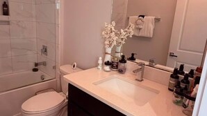 A bathroom with a glass shower enclosure, a white toilet, a vanity with a mirror, and a sink. - Modern 3BR Haus in Lake Nona Medical City (Orlando, FL, 32827)