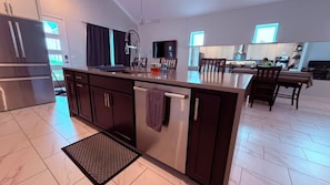 Una cocina moderna con una isla central, electrodomésticos de acero inoxidable y un comedor con sillas de madera.