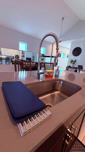 Una cocina moderna con un lavamanos de acero inoxidable, un tapete azul y un teclado de piano sobre la encimera.