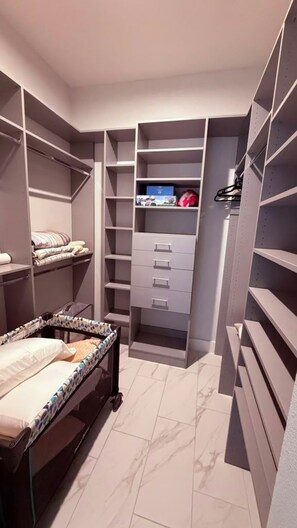 Un armario amplio con varias estanterías, cajones y una cama con colcha estampada.
