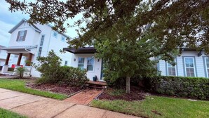 A residential building with a front porch, a small tree, and a paved driveway. - Modern 3BR Haus in Lake Nona Medical City (Orlando, FL, 32827)